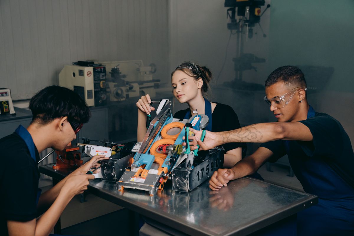 Tres estudiantes de bachillerato ajustan un proyecto de electrónica en el taller